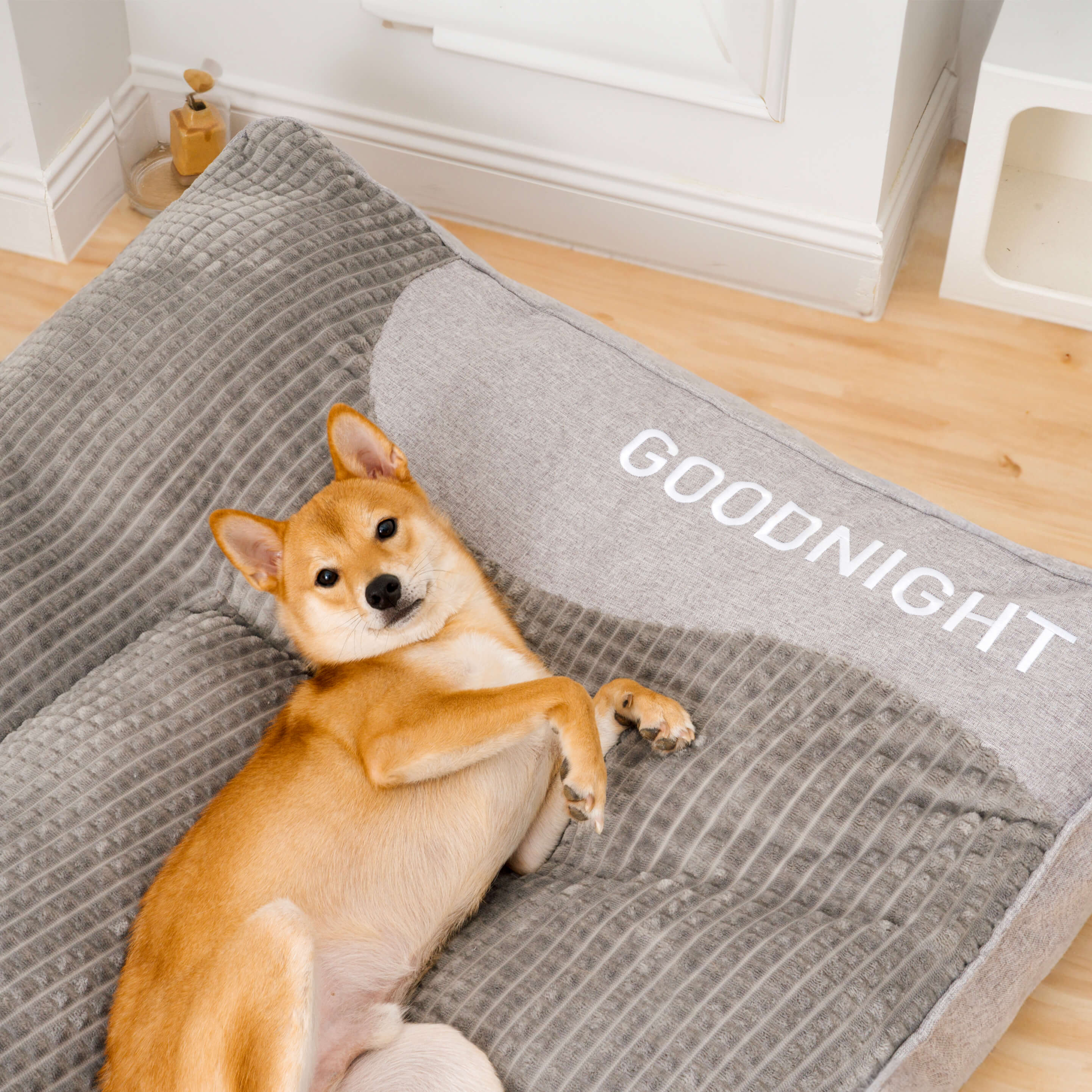 "Tykk ripebeskyttende hundeseng, myk, slitesterk med ryggstøtte, beige farge, i rom med stilfull innredning."