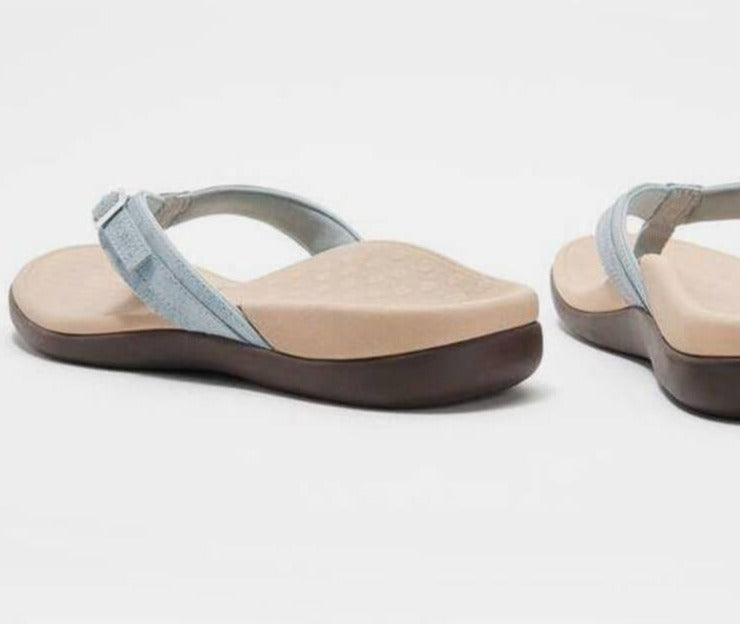 Modell som hviler foten med ortopediske flip-flops, viser avslappet komfort.