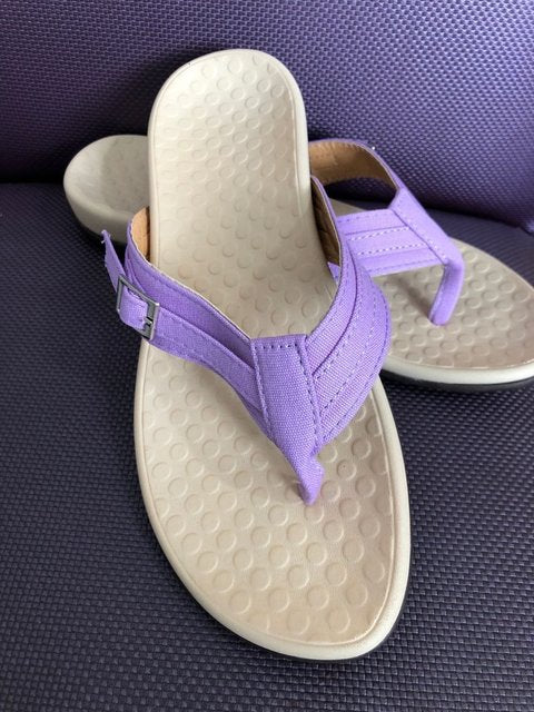 Detajlbilde av fotbuen i ortopediske flip-flops, som fremhever ekstra støtte.