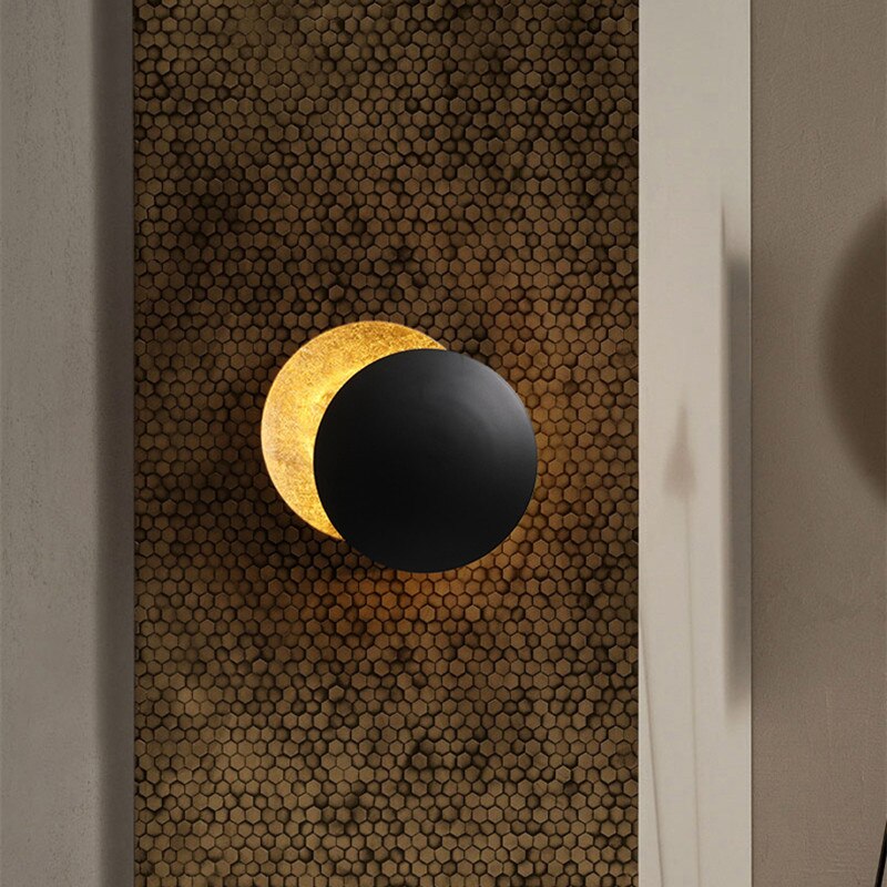 "Vegglampe med solformørkelseffekt, elegant design, to gylne roterende skiver, tilgjengelig i gull og kobber."