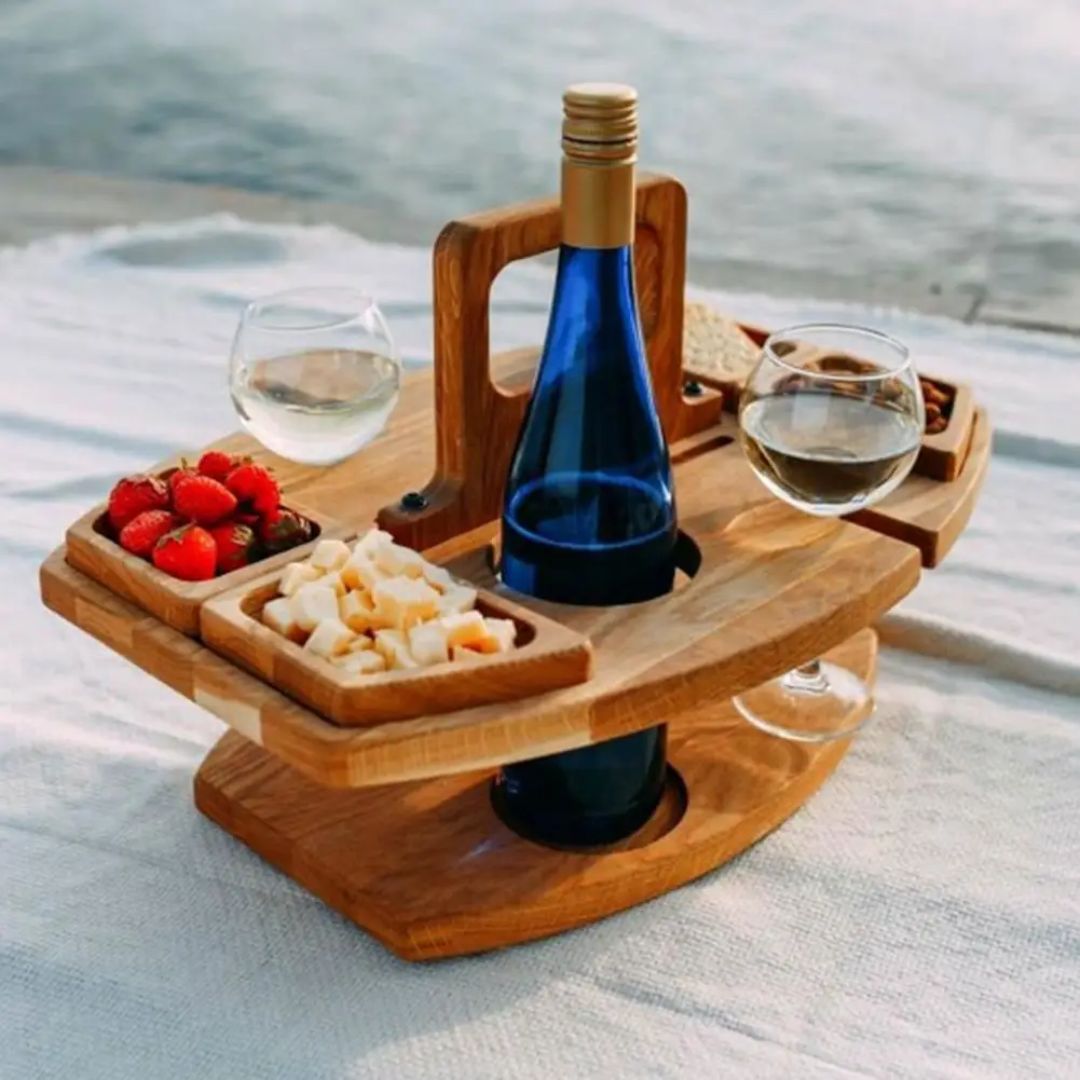 Sammenleggbart tre vinbord i beige, perfekt for utendørs bruk. Inkluderer vinglassholder og snackbrett.