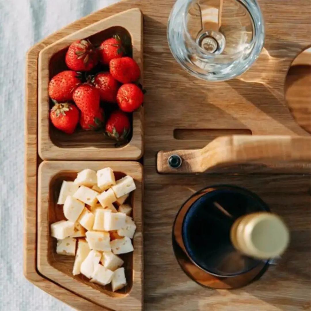 Tre piknikbord i beige, bærbart design med vinglassholdere for utendørs bruk.