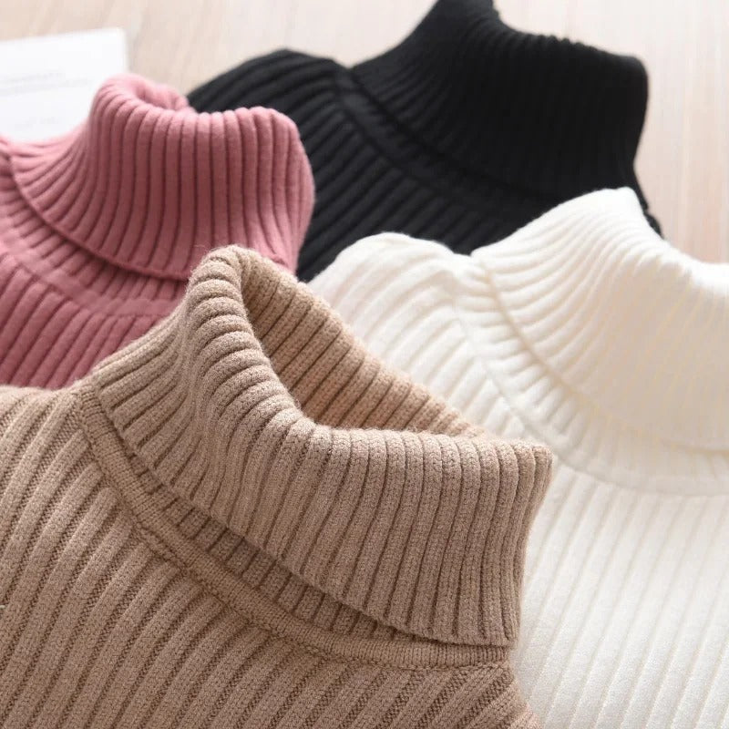 Barnemodell som viser passformen av en strikket turtleneck genser i nøytral farge