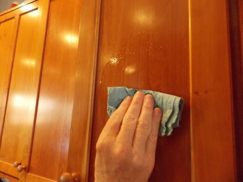 Hånd påfører bivoks på gammelt trebord, restaurering, trepleie, rengjøring, interiør