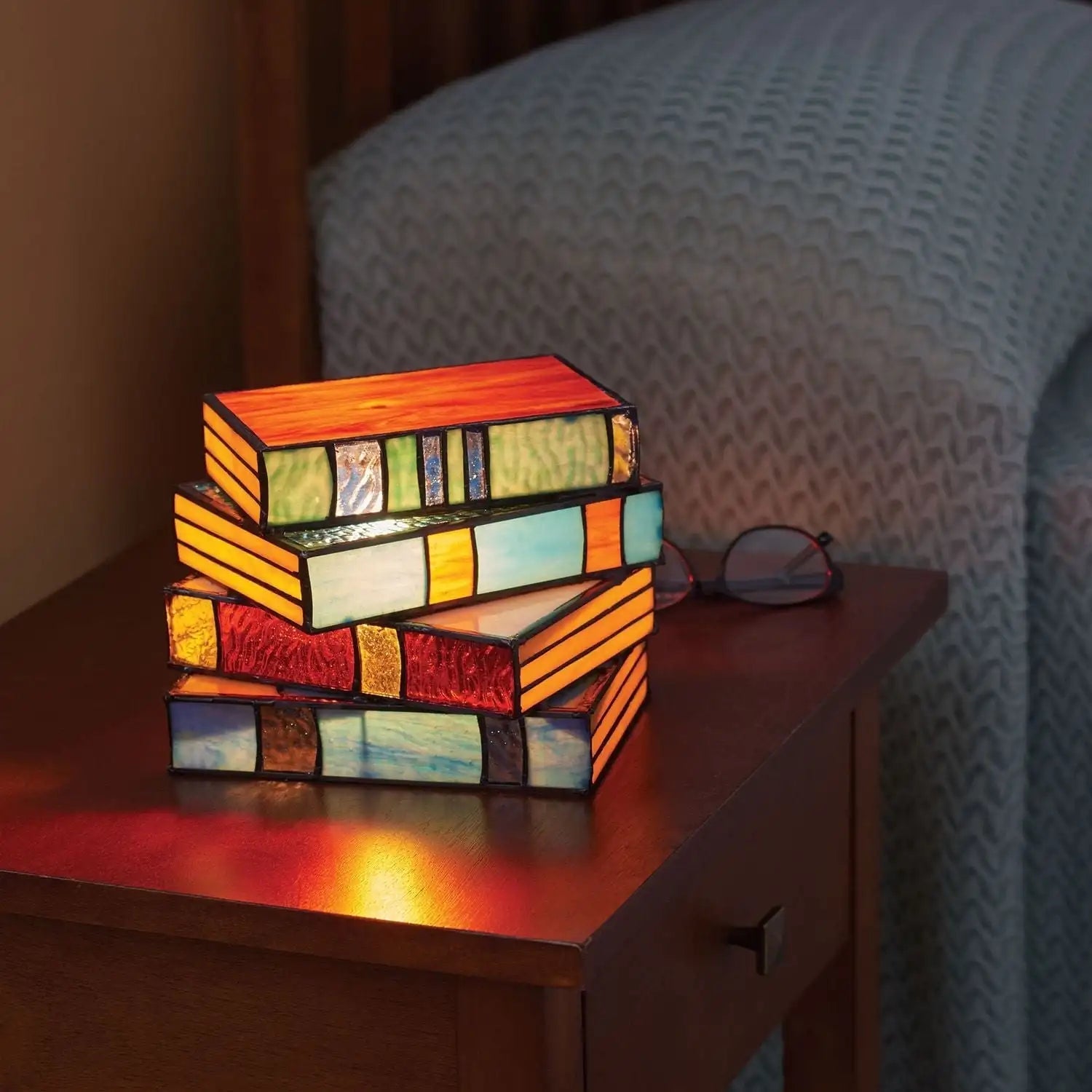 Håndlaget bordlampe med detaljert bokdesign og flerfarget glass, skaper koselig stemning i rommet.