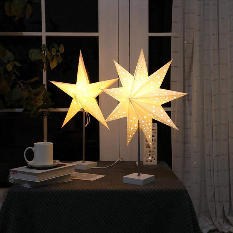 Bordlampe med stjernedesign i et mørkt rom, fremhever stemningslys og koselig atmosfære.