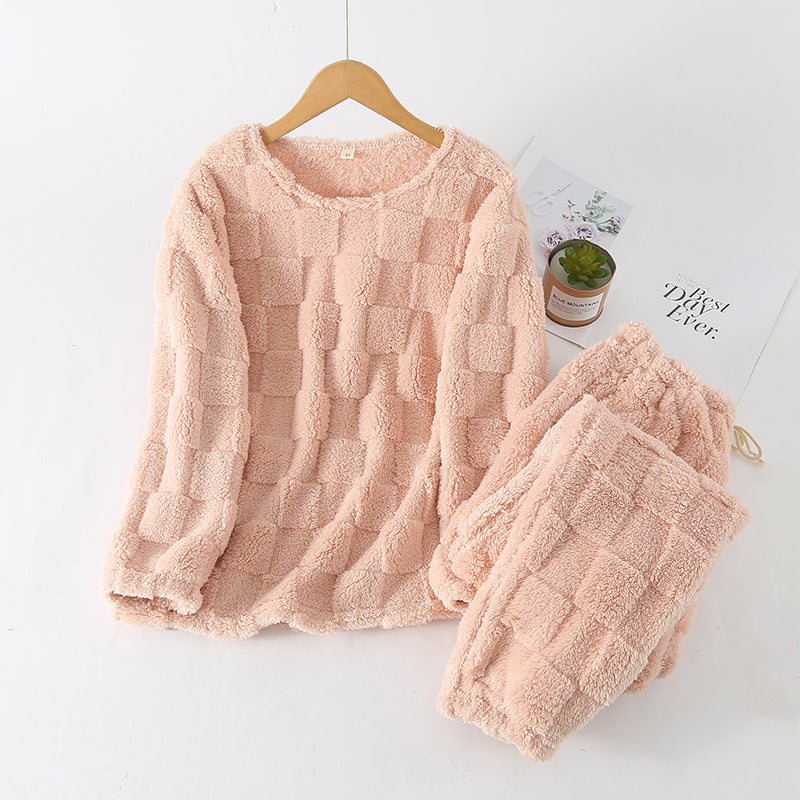 Kvinne sitter avslappet i lenestol iført elegant rutete pyjamassett, understreker luksuriøs loungewear-opplevelse.