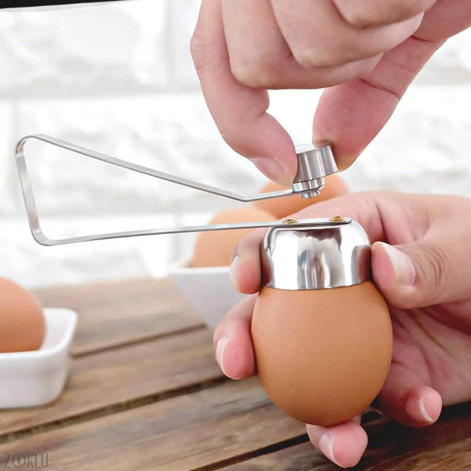 Hånd demonstrerer bruk av eggeknekkeren for å åpne et mykkokt egg, rask og sølfri eggeåpning.