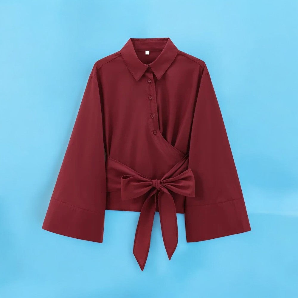 Detaljert bilde av sløyfen på en elegant, langermet kimonobluse for kvinner, som fremhever designet.