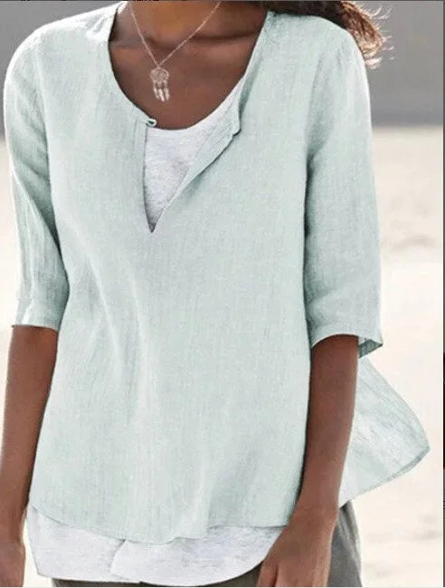 Damebluse med elegant v-hals og 3/4-ermer, vist på modell. Komfortabel passform for alle anledninger.