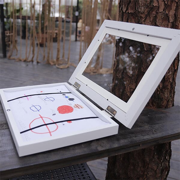 "Elegant, hvit 10x12,5 ramme for barnekunst, med glassfront og magnetlukking, ideell for tegninger og malerier."