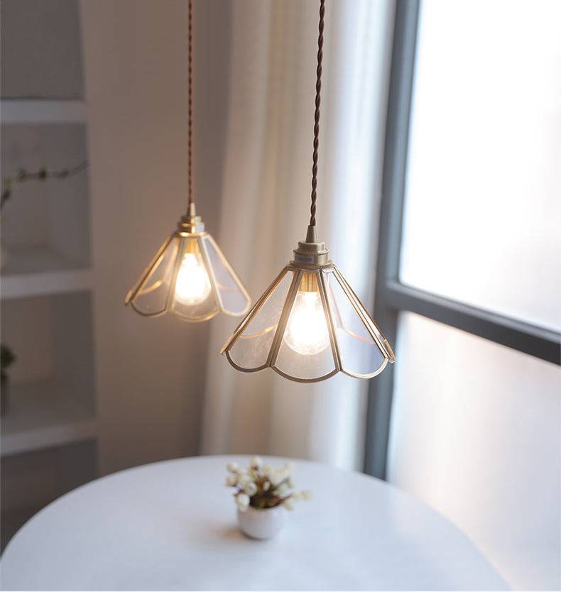 "Elegant pendellampe i messing og klart glass med vintage tvinnet stoffledning, gir en klassisk og moderne belysning."
