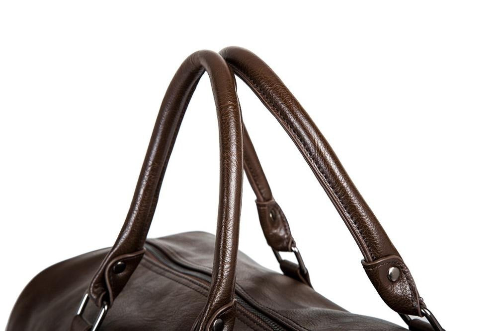 Menns elegant duffelbag i skinn plassert på et bagasjebrett, klar for reise med praktisk og stilig design.