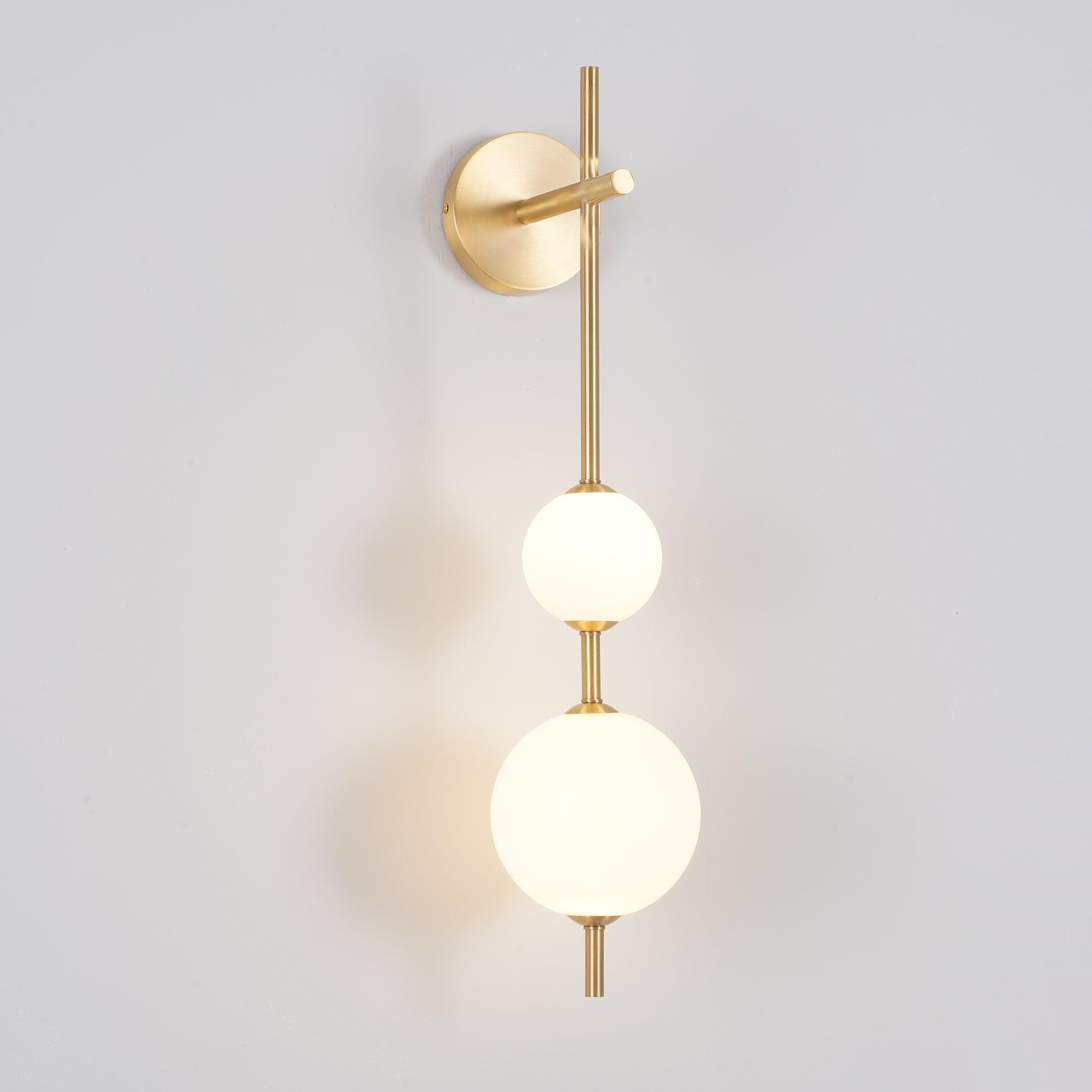 "Elegant vegglampe i glass og messing med kuleformede skjermer for mykt lys, perfekt for moderne og klassiske hjem."
