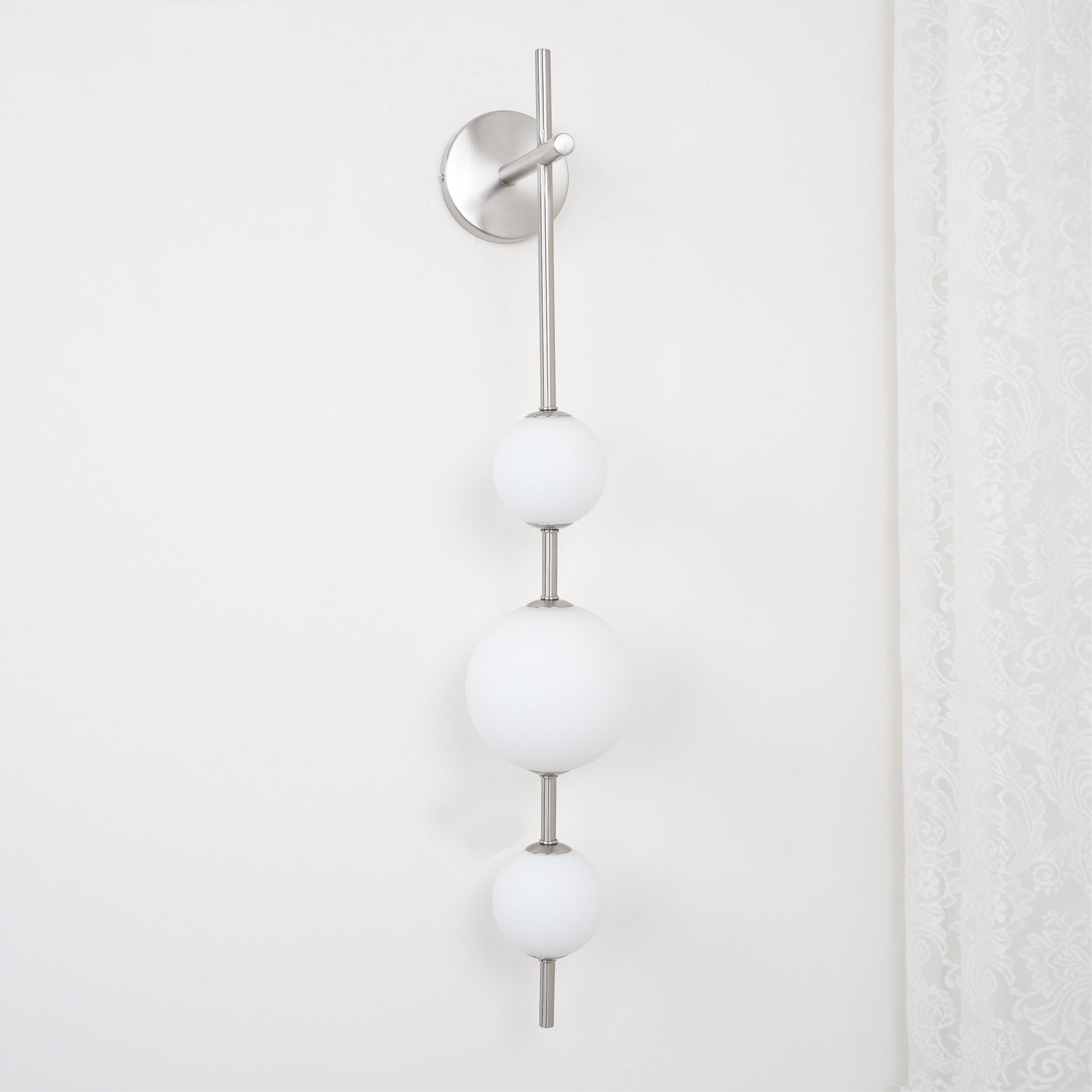 "Elegant vegglampe i glass og messing med kuleformede skjermer for mykt lys, perfekt for moderne og klassiske hjem."