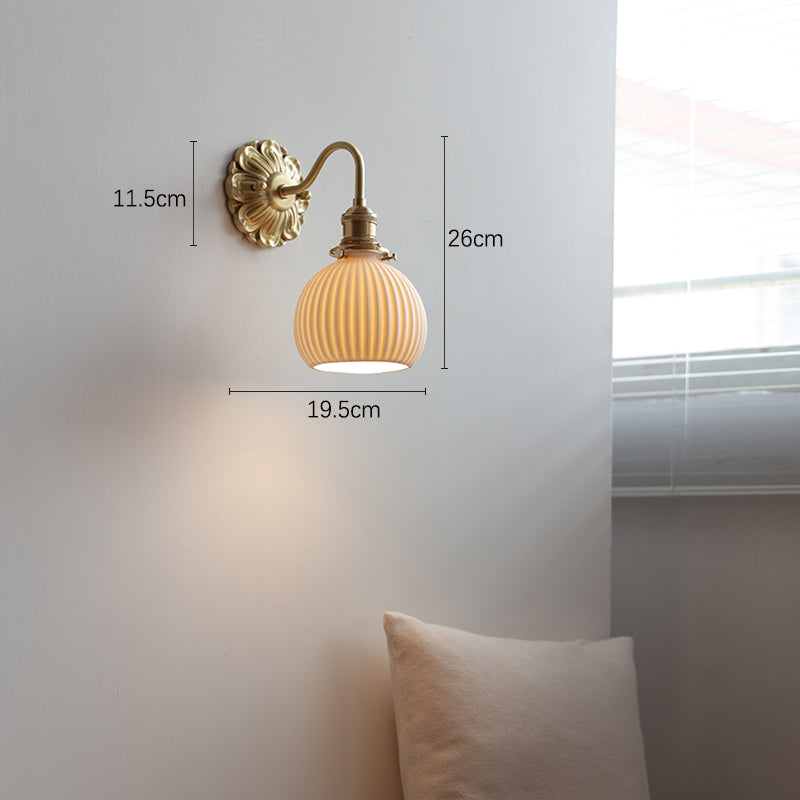 "Elegant vegglampe i messing og keramikk med antikk finish og hvit lampeskjerm, gir klassisk preg til interiøret."