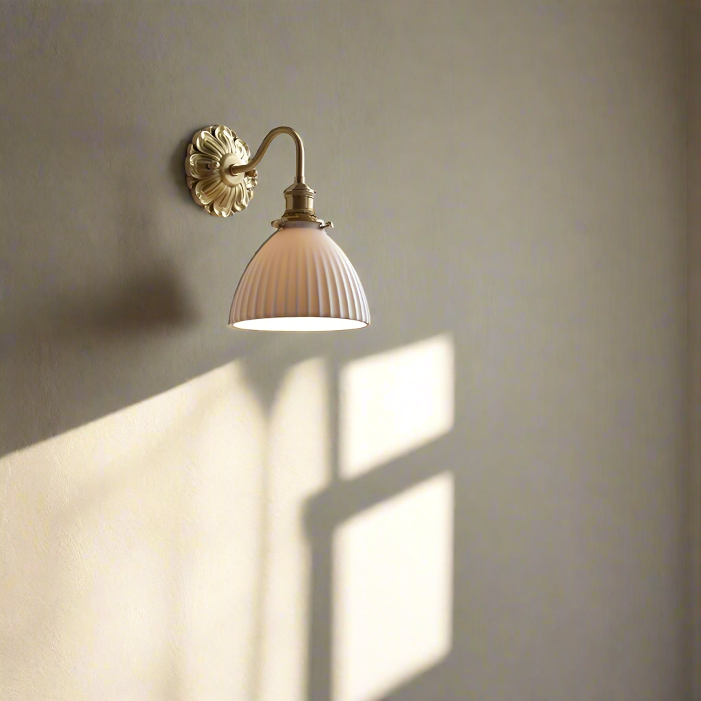"Elegant vegglampe i messing og keramikk med antikk finish og hvit lampeskjerm, gir klassisk preg til interiøret."