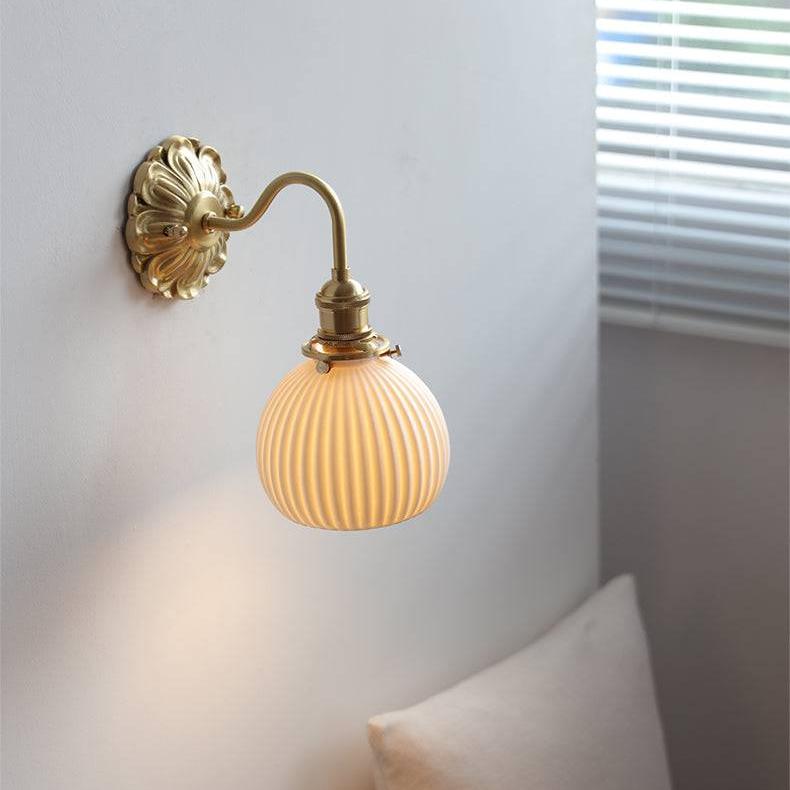 "Elegant vegglampe i messing og keramikk med antikk finish og hvit lampeskjerm, gir klassisk preg til interiøret."