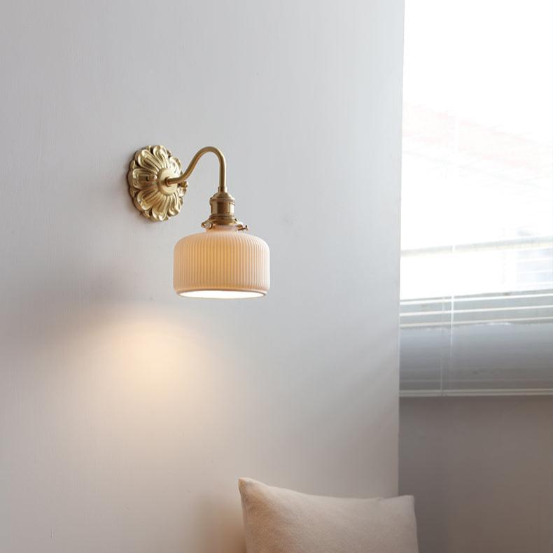 "Elegant vegglampe i messing og keramikk med antikk finish og hvit lampeskjerm, gir klassisk preg til interiøret."