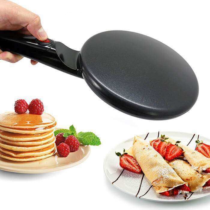 Bruk av elektrisk crêpe maker: en tynn pannekake stekes, med tilbehør som bær og sirup i bakgrunnen.