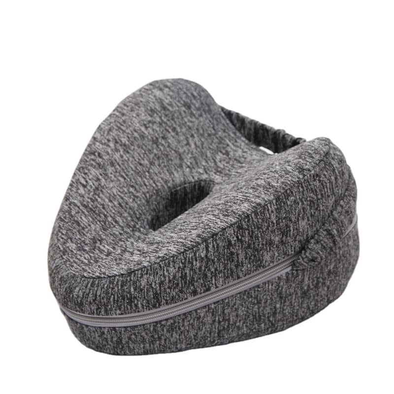 "Ergonomisk hjerteformet knepute i grått minneskum for avlastning, plassert mellom bena for støtte og bedre søvn."
