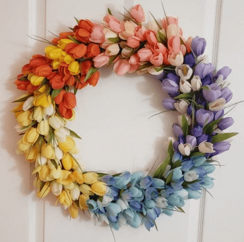 Elegant tulipankrans på en hvit dør, skaper sommerlig og innbydende stemning.