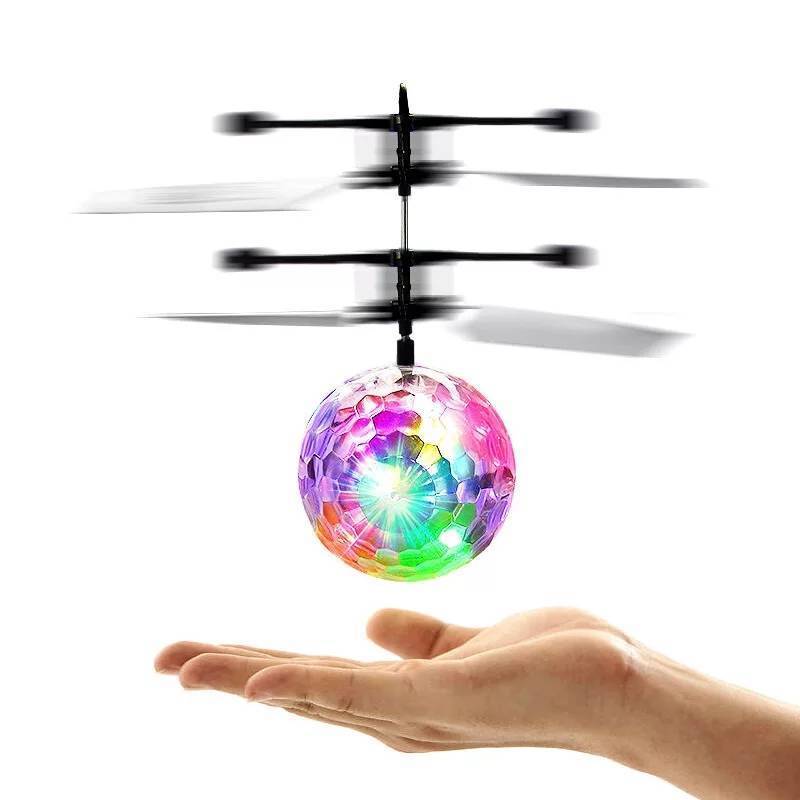Barn ler mens de observerer en flygende LED helikopterdrone innendørs, uten fjernkontroll