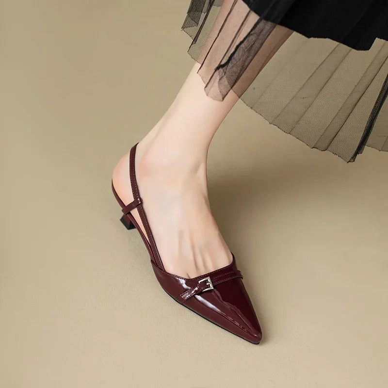 Detalj av skinnende damesandaler, fremhever den mellomhøye hælen og slingback-designet.