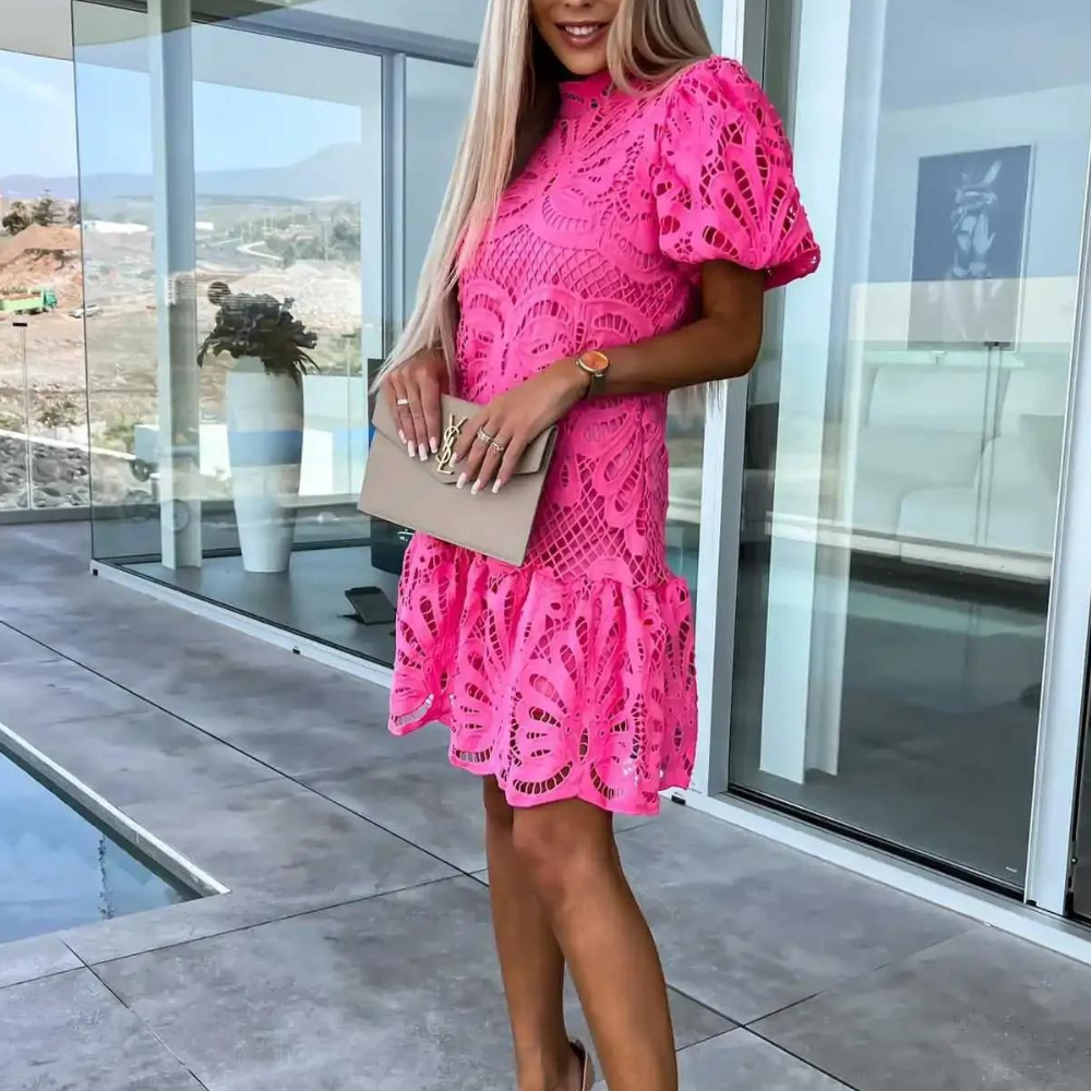 "Gwenda sommerkjole i rosa med delikate blonder og puffermer, perfekt for sommerens formelle og uformelle anledninger."