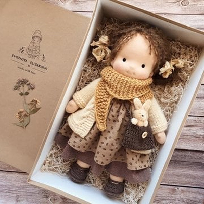 Håndlaget Waldorf-dukke i økologisk bomull med polka dots, brun og lilla kjole. Perfekt for småbarn, myk og trygg.