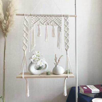 Detaljert bilde av hvit macramé hylle med intrikate knuter og frynser, skaper bohemsk interiør.