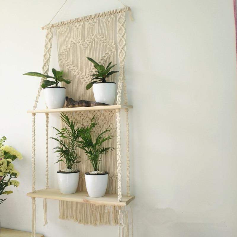 Fullt bilde av en stilren, hengende macramé vegghylle med potteplante, flott boho veggdekor.