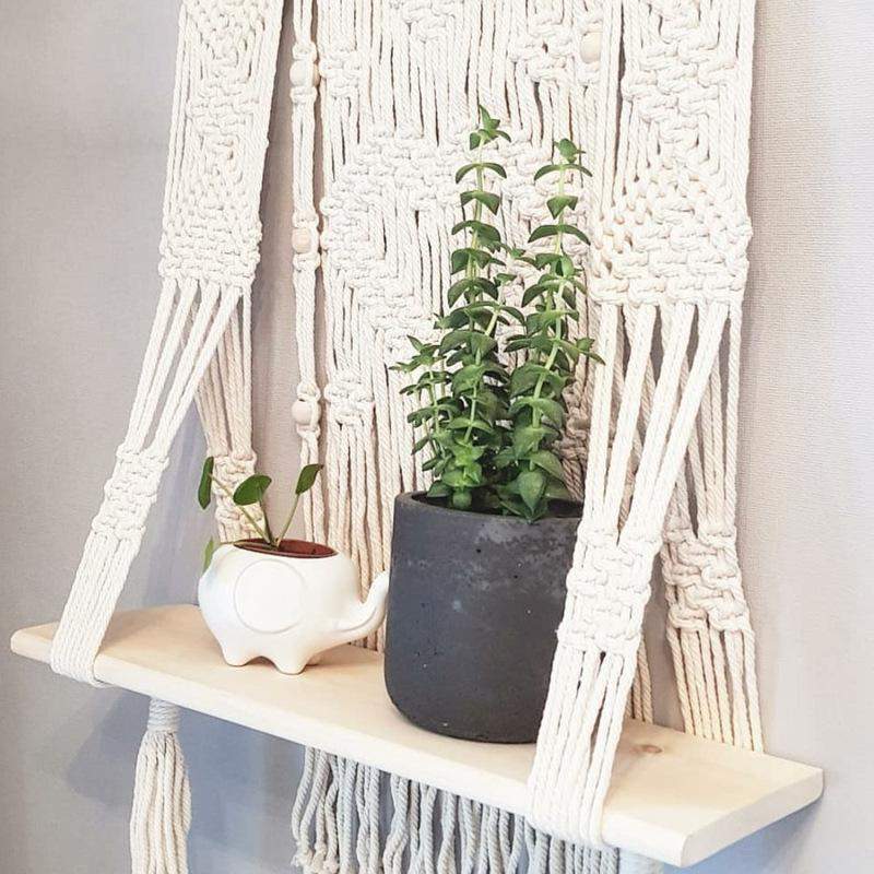 Minimalistisk hengende macramé vegghylle, perfekt for å tilføre et bohemsk preg til hjemmet.