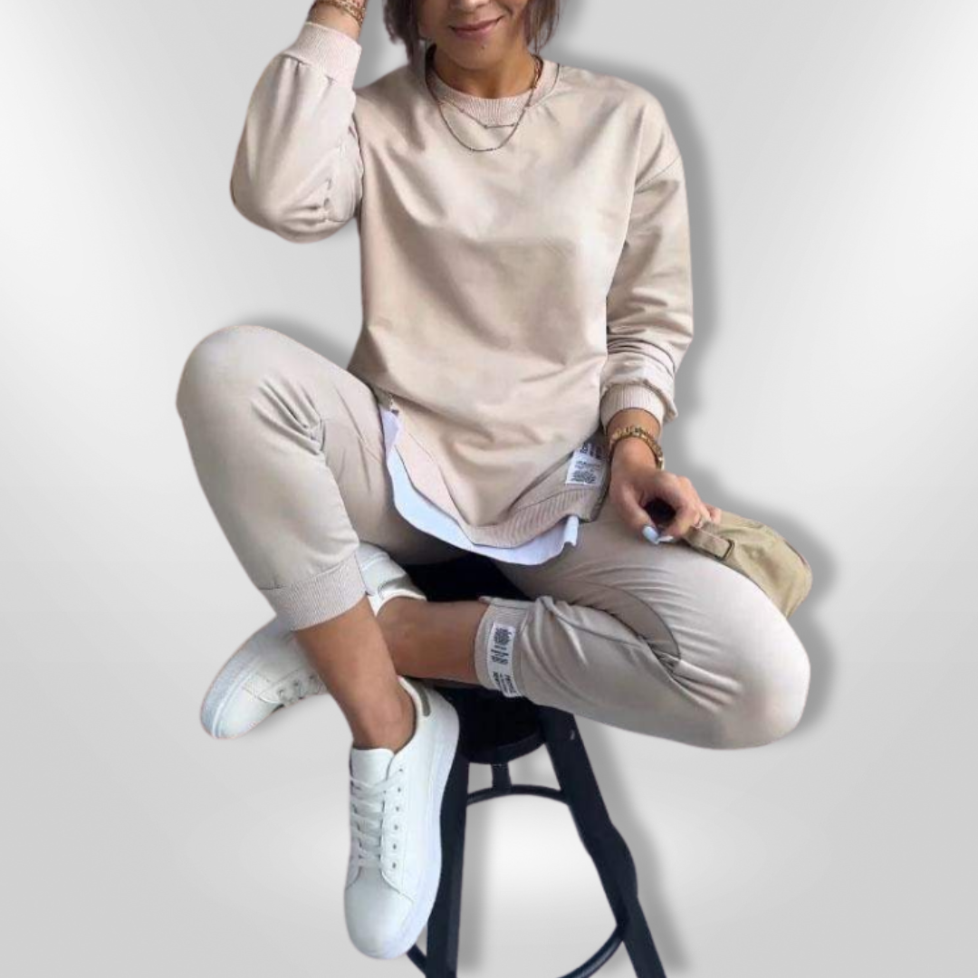 Kvinne i avslappet beige hjemmeantrekk; oversized sweatshirt og joggers. Perfekt for komfort.