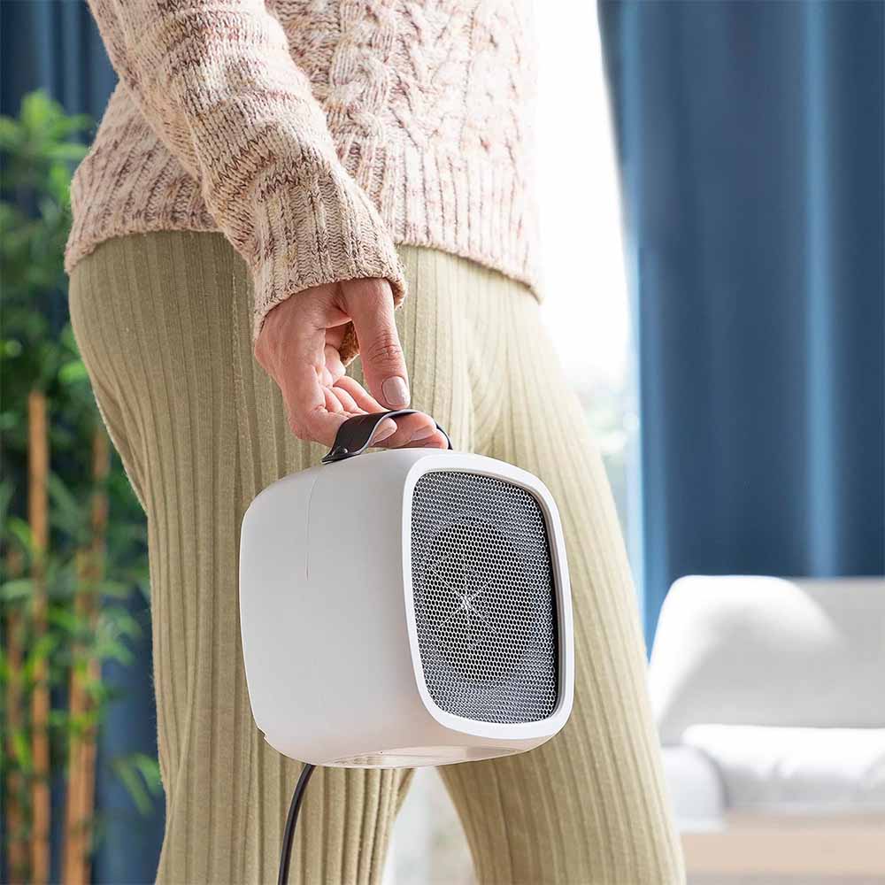 Energieffektiv, hvit mini varmevifte varmer et hjemmekontor. Kompakt og stilrent design.