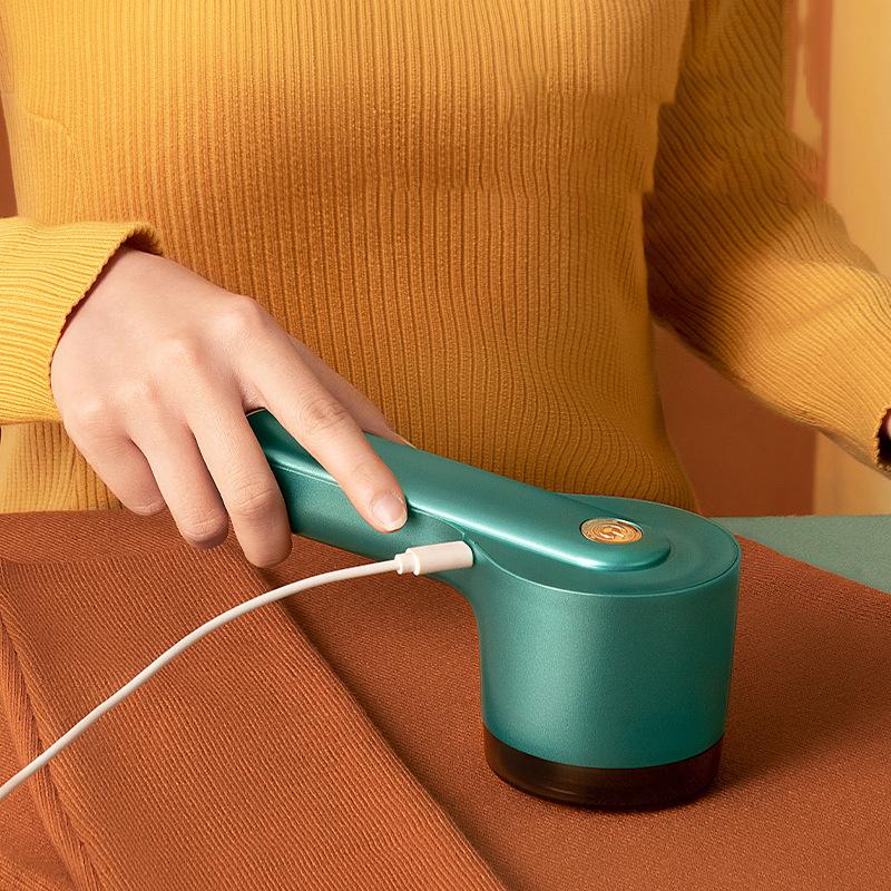 "Liten oppladbar lofjerner i grønt for skånsom stoffpleie, vises med USB-port for enkel lading og kompakt design."