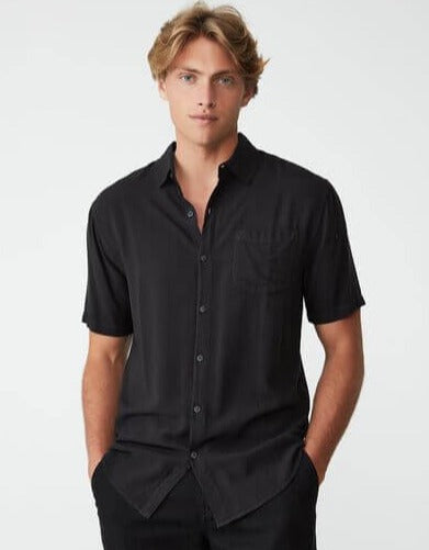 Nærbilde av kragen og knappene på en mørk grønn poloskjorte, fremhever detaljer og håndverk.