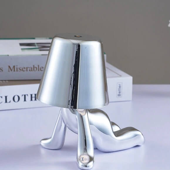 Fra siden: moderne bordlampe i metall, viser unik form og LED-lysets retning, innovativ innredning.