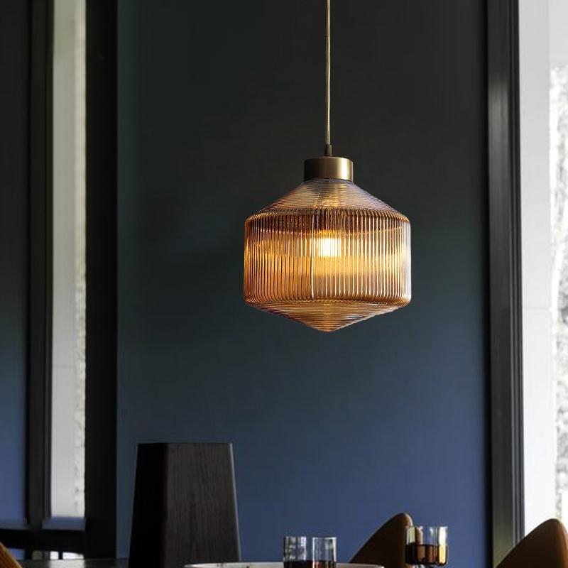 "Moderne pendellampe i amber med trommeldesign, vist med røykgrå og klar fargealternativ, perfekt for stilig interiør."