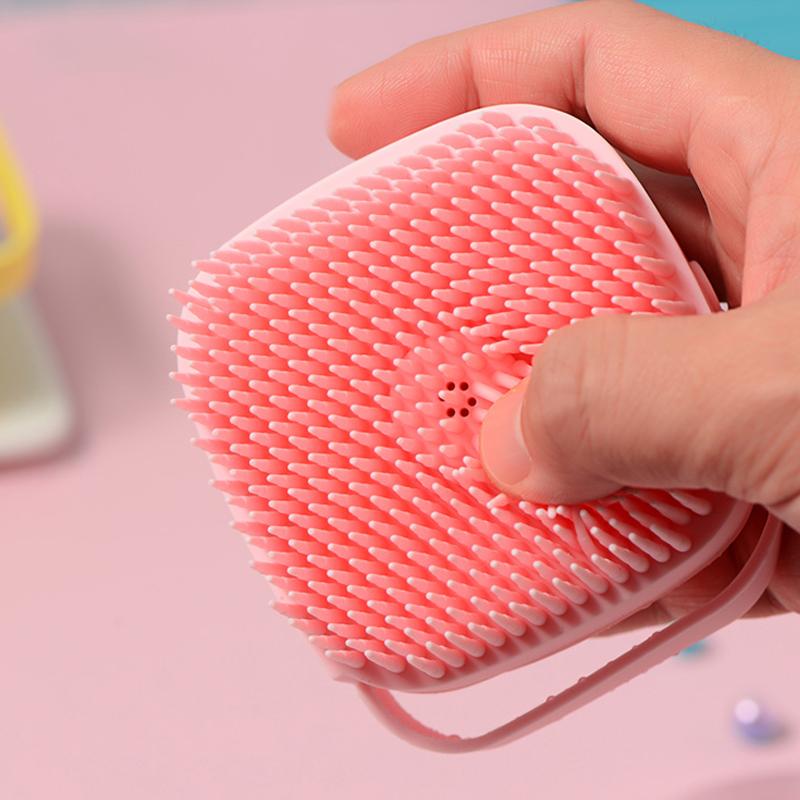 "Myk silikonbadbørste i rosa, gul eller blå. Kompakt, slitesterk og designet for enkel hårrengjøring og massasje."