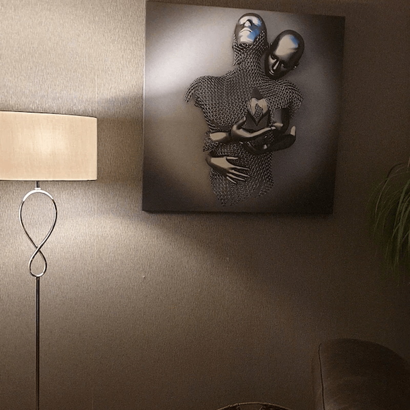 Romantisk kunstmaleri til vegg i lerret, viser et omfavnende par med hjerte i sølv- og gyllen toner. Perfekt for soverom.