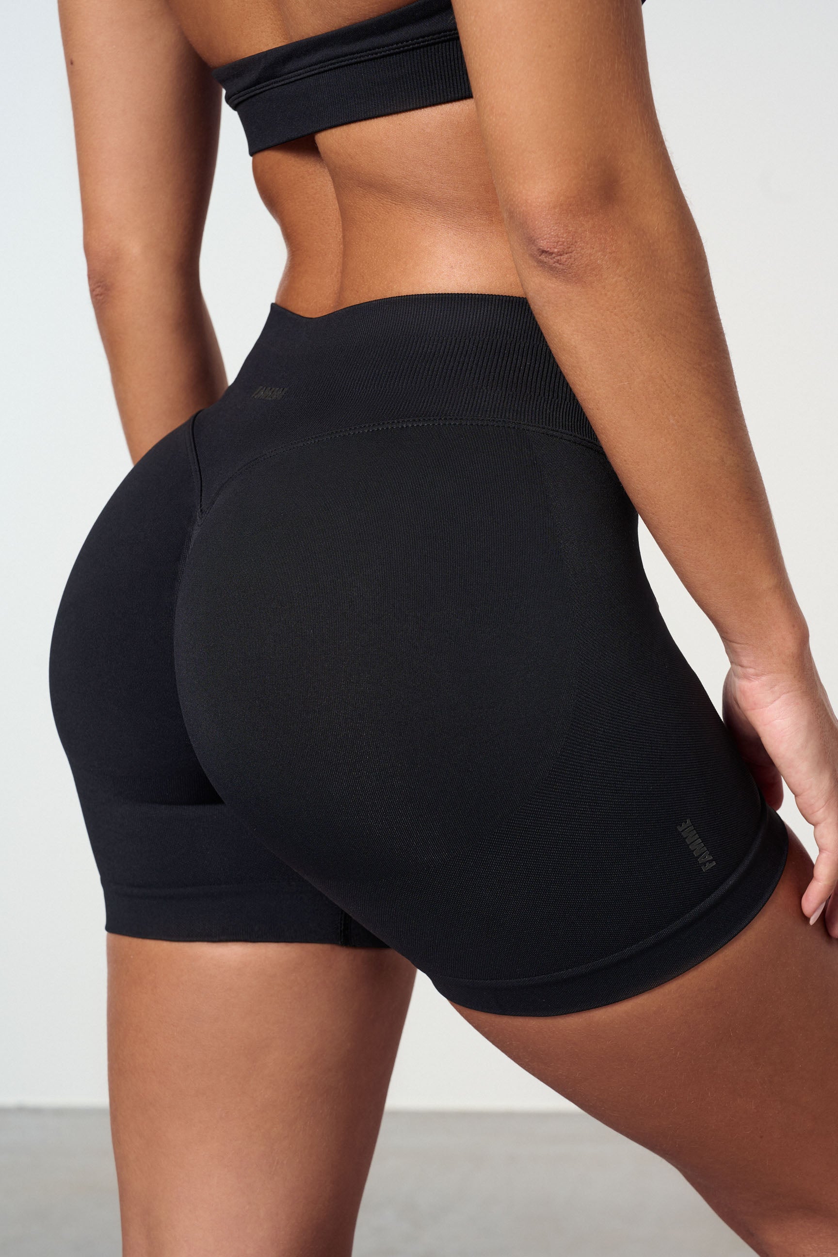 "Sømløse treningsshorts med scrunch-effekt for kurver, sort, sett forfra. Komfortabel med mid waist og 4-veis stretch."