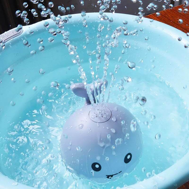 Nærbilde av hvalens dyse som sprinkler vann, mens fargerike LED-lys lyser opp leken.