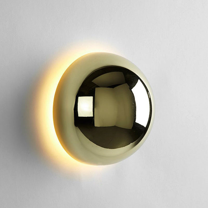 "Stilfull vegglampe med rund silhuett, gull finish og solformørkelseseffekt. Perfekt for moderne og middelalderlig interiør."