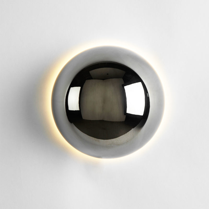 "Stilfull vegglampe med rund silhuett, gull finish og solformørkelseseffekt. Perfekt for moderne og middelalderlig interiør."