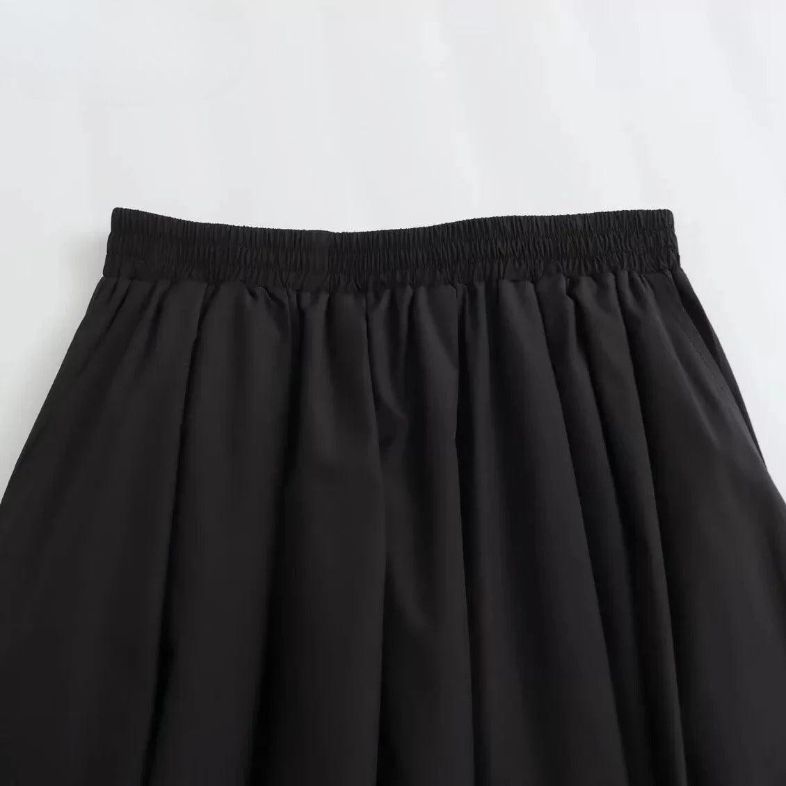 Elegant svart plissert A-linje skjørt for dame, viser lett fall og bevegelse.