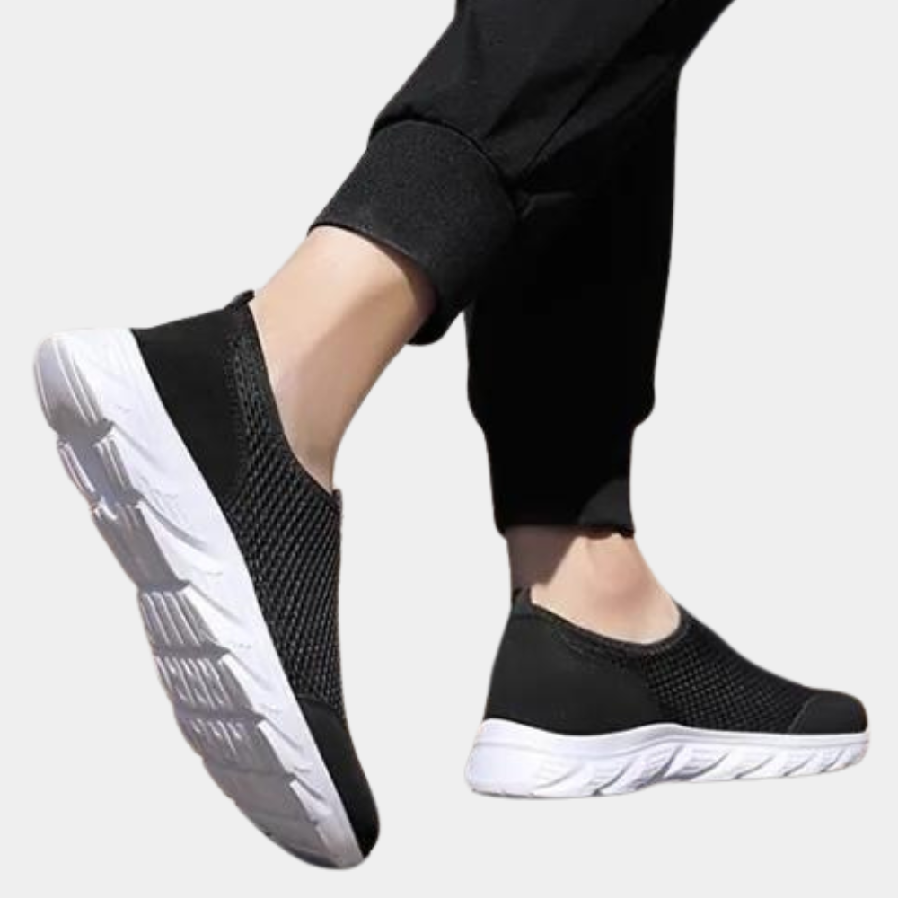 "Svart slip-on herresko med pustende netting og hvit såle. Komfortabel og slitesterk for daglig bruk."
