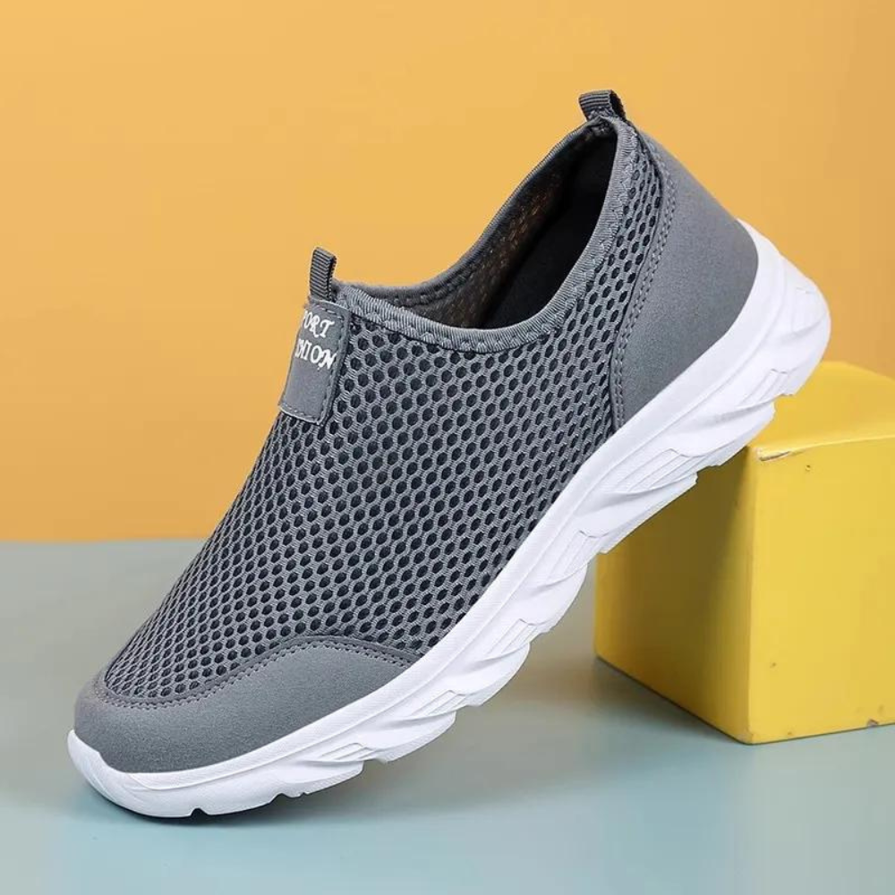 "Svart slip-on herresko med pustende netting og hvit såle. Komfortabel og slitesterk for daglig bruk."