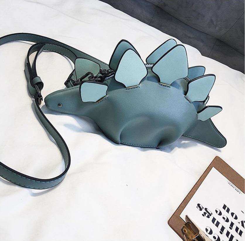 Detaljert bilde av en grønn 3D-dinosaur skulderveske for barn, med realistisk tekstur og glidelås.