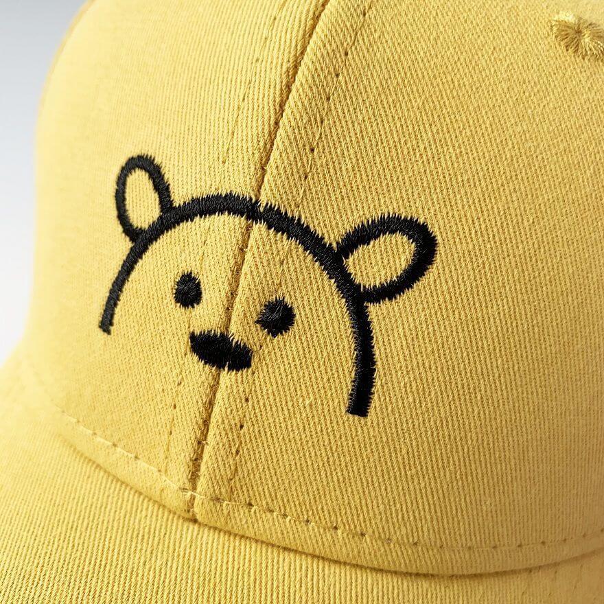 Modell med barne bjørnelue som smiler. Unisex solhatt gir solbeskyttelse og er et stilig tilbehør.